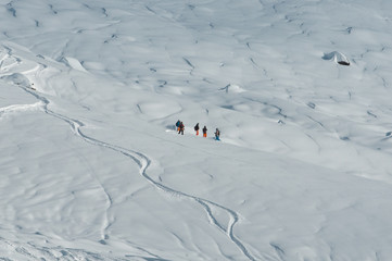 A group of snowboarders standing on the slope covered with traces and waiting for the other group...