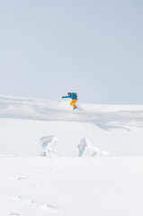 Naklejka na ściany i meble A snowboarder jumping off the cornice in a bright sunny day