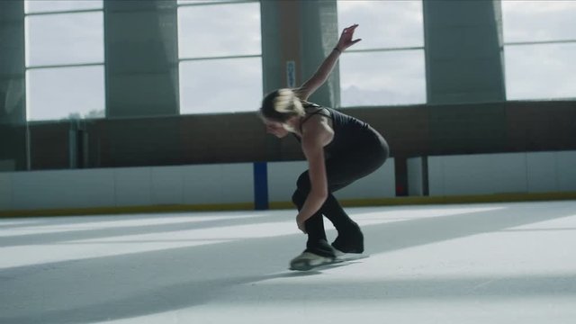 Slow motion of distant woman practicing figure skating on ice skating rink / Murray, Utah, United States