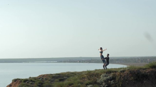 meditation at nature, couple practicing acro yoga, girl one leg is balancing on the foots of her male partner on background of sea and sky