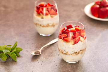 Homemade yogurt parfait with granola, strawberries, bananas and Chia seeds in glasses. Diet dessert with yogurt, Chia, muesli and fresh berries. Healthy breakfast 