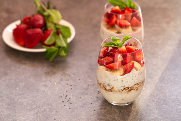 Homemade yogurt parfait with granola, strawberries, bananas and Chia seeds in glasses. Diet dessert with yogurt, Chia, muesli and fresh berries. Healthy breakfast 