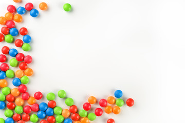 Frame of multi-colored candies close up. Rainbow colored dragee multicolored glaze on a white...