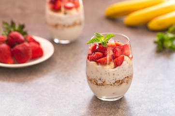 Homemade yogurt parfait with granola, strawberries, bananas and Chia seeds in glasses. Diet dessert with yogurt, Chia, muesli and fresh berries. Healthy breakfast 