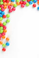 Frame of multi-colored candies close up. Rainbow colored dragee multicolored glaze on a white background