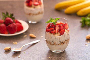 Homemade yogurt parfait with granola, strawberries, bananas and Chia seeds in glasses. Diet dessert with yogurt, Chia, muesli and fresh berries. Healthy breakfast 