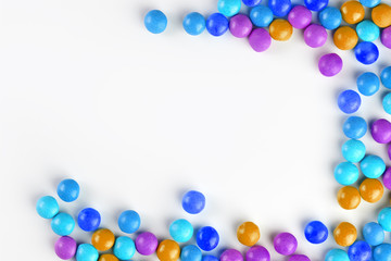 Frame of multi-colored candies close up. Rainbow colored dragee multicolored glaze on a white background