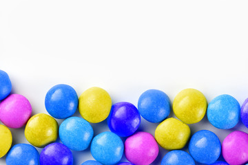 Frame of multi-colored candies close up. Rainbow colored dragee multicolored glaze on a white background