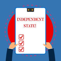 Handwriting text writing Independent State. Conceptual photo ability of the state to be independent and have autonomy White rectangle clipboard with blue frame has two holes holds by hands