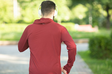 Male runner running on road training for fitness. Man doing jogging workout run outside in summer in nature