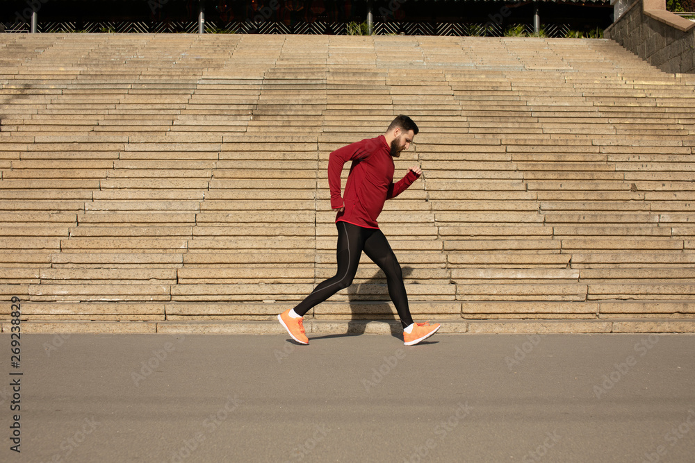 Wall mural Muscular sportsman running stairs background. Morning workout. Urban scene. Fitness, sport, recreation, workout, healthy lifestyle concepts.