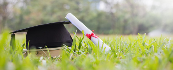 Closeup certificate paper and black cap on green grass spring time in the outdoor park. Education...