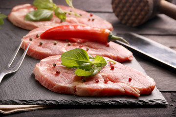 Raw pork meat steak with vegetables, peppers, tomato, salt, rosemary and spices cooking over stone table. Top view.