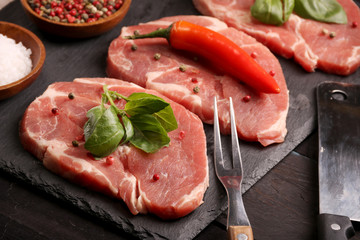 Raw pork meat steak with vegetables, peppers, tomato, salt, rosemary and spices cooking over stone table. Top view.