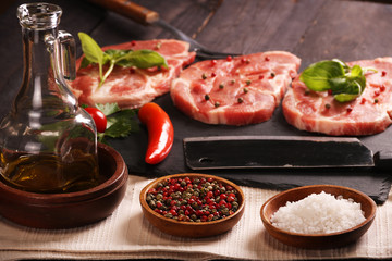 Raw pork meat steak with vegetables, peppers, tomato, salt, rosemary and spices cooking over stone table. Top view.