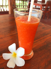 Freshly squeezed glass of juice  with a straw and a Plumeria flower