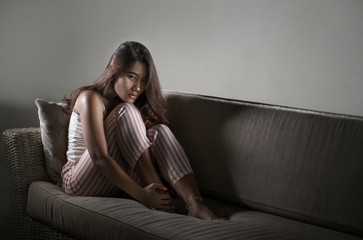 Fototapeta premium young sad and depressed Asian Indonesian woman sitting at home couch crying frustrated and upset suffering stress and depression after breakup