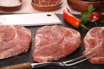 Raw pork meat steak with vegetables, peppers, tomato, salt, rosemary and spices cooking over stone table. Top view.
