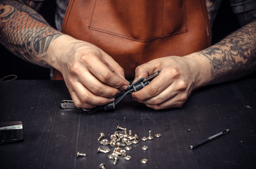 Obraz premium Leather workman creates quality product of leather at his place of work