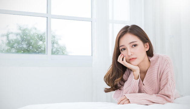 Portrait of young beautiful asian woman feeling depress stressful in bedroom. Sad face asian girl sitting near window in winter. Beauty perfect clear skin japanese makeup  lifestyle concept banner