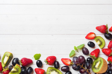 Fresh fruit strawberry kiwi grapes on white table with copy space.