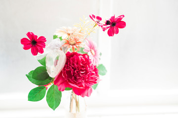 transparent vase with colorful flowers against white background
