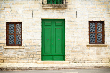 Architecture details from the Renaissance - green painted wooden door and two windows with a grate of a stone house in Kavarna city, Bulgaria