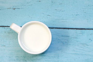 White cup with milk on a blue wooden table. Background.
