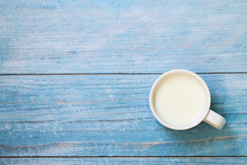 White cup with milk on a blue wooden table. Background.