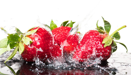 Several ripe wet red strawberries on white or colored background with splashes of water