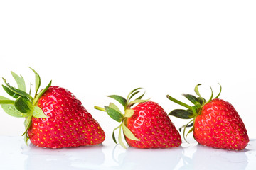 Several ripe wet red strawberries on white or colored background with splashes of water