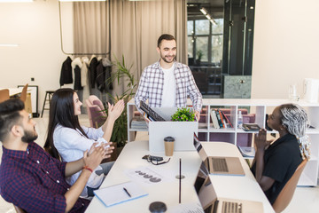 Company members gathered in office greeting newcomer man employee. New worker holds carton box with personal belongings starting career in company feels proud happy