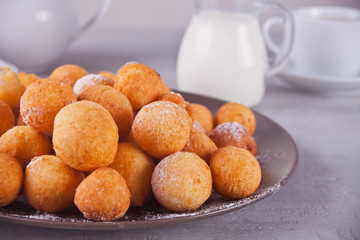 Small balls of freshly baked homemade cottage cheese doughnuts in a plate on a gray background.