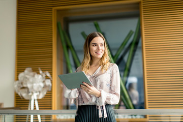 Attractive businesswoman using a digital tablet while standing in the office