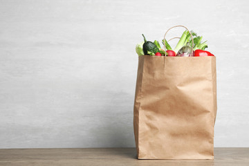Paper bag with vegetables on table against grey background. Space for text