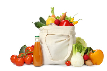Cloth bag with fresh vegetables and bottle of juice on white background