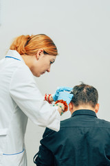 A young man with a bald spot in the office of a trichologist cosmetologist. Mesotherapy of hair and...