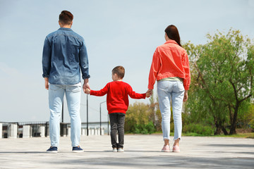 Little child holding hands with his parents outdoors. Family weekend