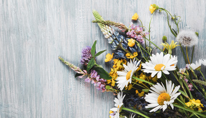 Wild flowers on old grunge wooden background (chamomile lupine dandelions thyme mint bells rape)