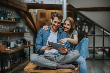 Young couple is using a digital tablet and smiling in kitchen at home