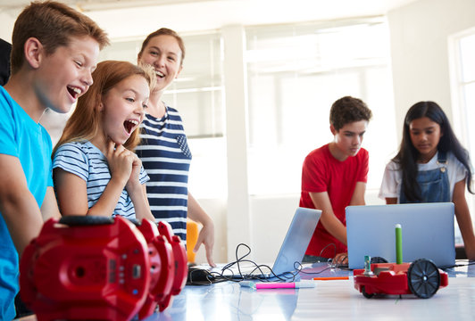 Excited Students Watching Robot Vehicle Move After Coding Lesson In Computer Programing Class