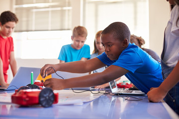 Group Of Students In After School Computer Coding Class Learning To Program Robot Vehicle