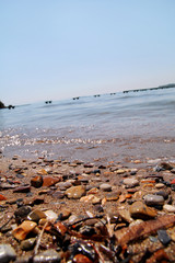 Exotic rocky beach with colorful stones, tropical blue sea with waves and foam. Beautiful natural environment, panorama, landscape. Idyllic seaside resort in summer season, paradise, amazing scene.