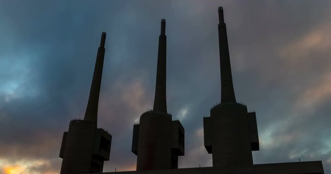 Ancient thermal power station in Sant Adria, province of Barcelona.Hyper Lapse. Silhouette of three chimneys with clouds in motion on sunset sky background.   Smooth camera movement: Zoom in.