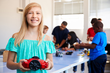 Portrait Of Female Student Building Robot Vehicle In After School Computer Coding Class