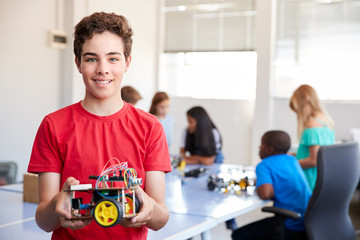 Portrait Of Male Student Building Robot Vehicle In After School Computer Coding Class