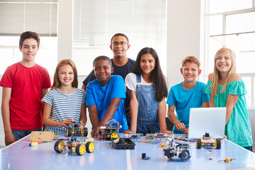 Portrait Of Students With Teacher Building Robot Vehicle In After School Computer Coding Class