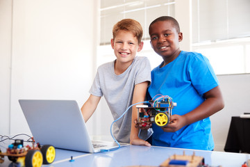 Portrait Of Two Male Students Building And Programing Robot Vehicle In School Computer Coding Class