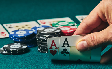 close-up of two aces held in one hand on the green game mat on the right side of the image to leave...