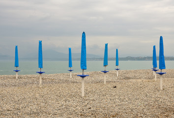 Eight blue beach umbrellas and stormy weather